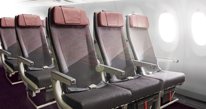 Seats in multiple rows, three across, photographed with an airplane window in the background.